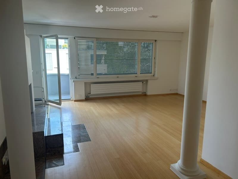 Empty room with wooden flooring, large windows, and a radiator under the windows. No furniture or equipment present.