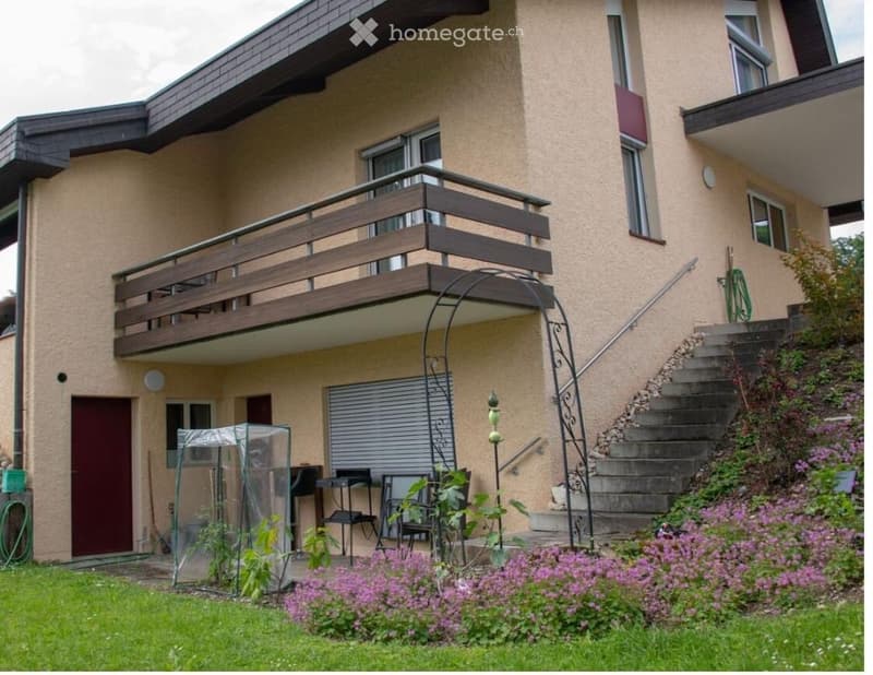 Detached house, beige wall, brown balcony, red door, white shutters, red door, shrubs, garden area