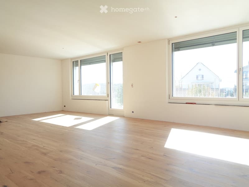 Empty room with light wooden flooring, white walls, and large windows allowing natural light to enter. No furniture or equipment is present.