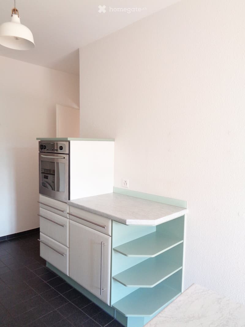 Modern kitchen with white cabinets, a built-in oven, a countertop, and a glass shelf unit.