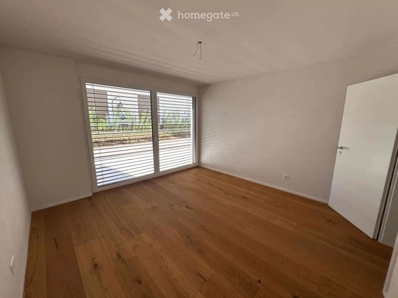 Empty room with wooden flooring, large sliding glass doors, and white walls.