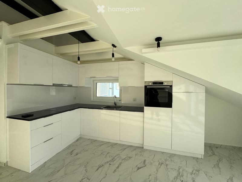 Modern kitchen with white cabinets, black countertops, marble flooring, and built-in oven.