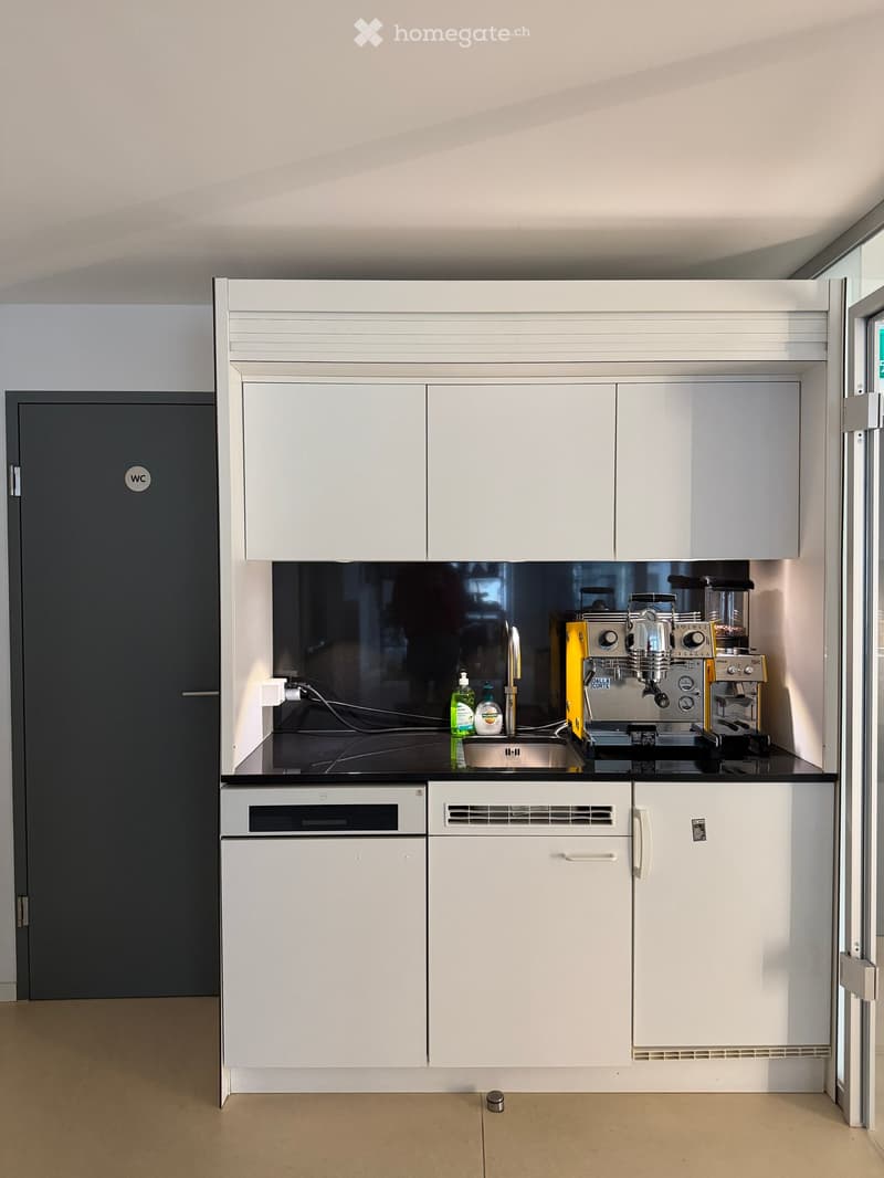 modern kitchen with white cabinets, black countertops, stainless steel sink, coffee machine, and dishwasher