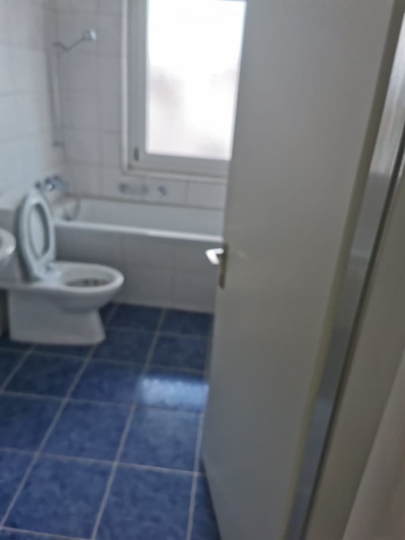 Bathroom with toilet, bathtub, and white tile flooring, with a white door