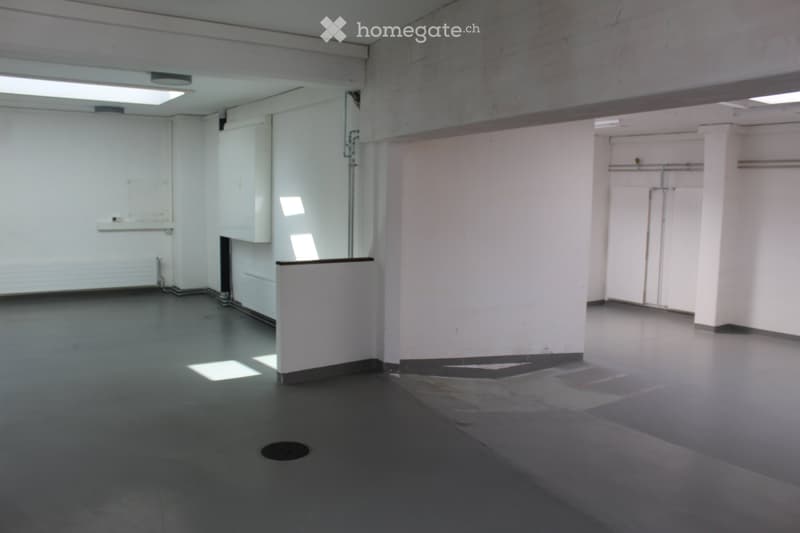 Empty room with white walls, grey concrete floor, and minimal structural elements. No furniture or personal items present.