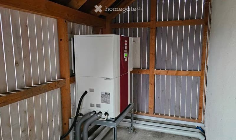 A room with a white and red appliance, pipes, and wooden walls