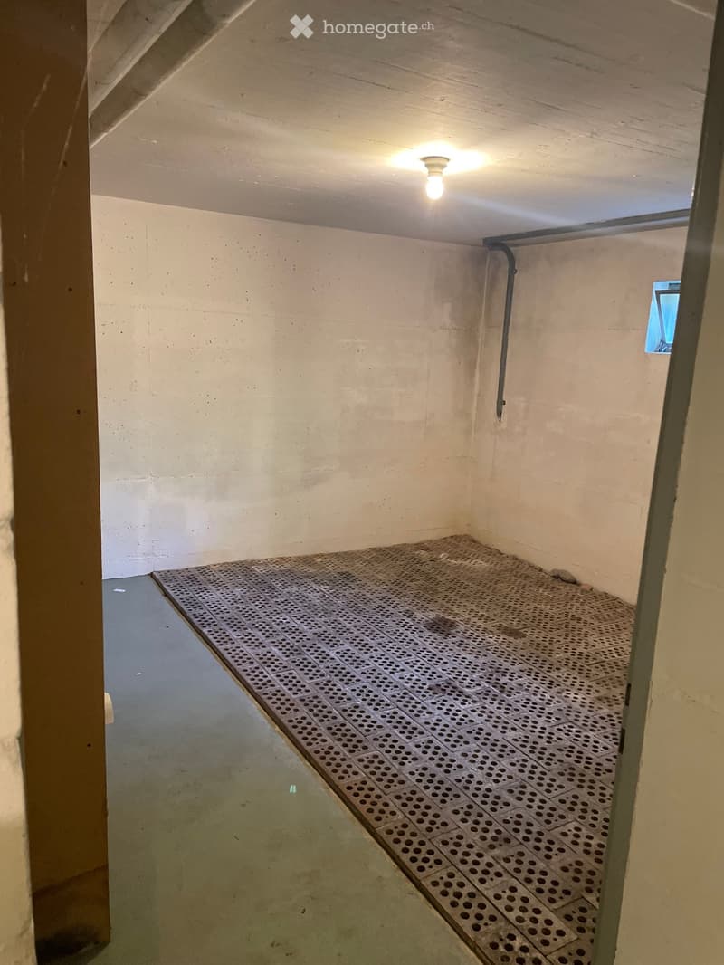 Empty room with concrete walls, a metal grated floor, and a small window. No furniture or equipment is present.