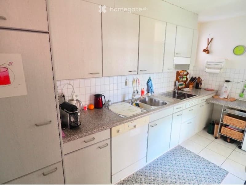 Modern kitchen with white cabinets, granite countertops, stainless steel sink, dishwasher, coffee maker, and various kitchen utensils.