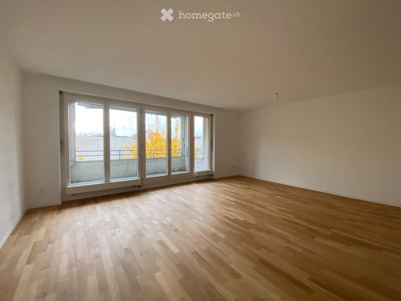 Empty room with wooden flooring and large windows, no furniture or equipment present.