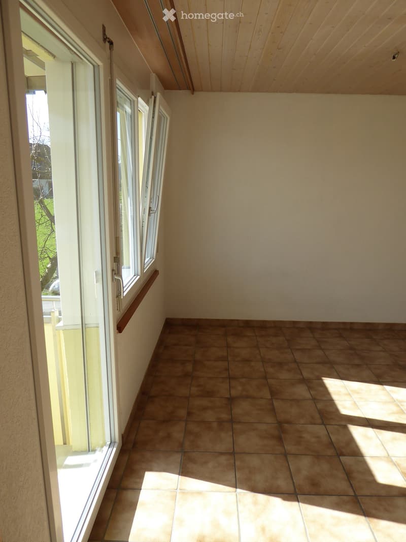 Empty room with tiled floor and large windows, allowing natural light to fill the space.