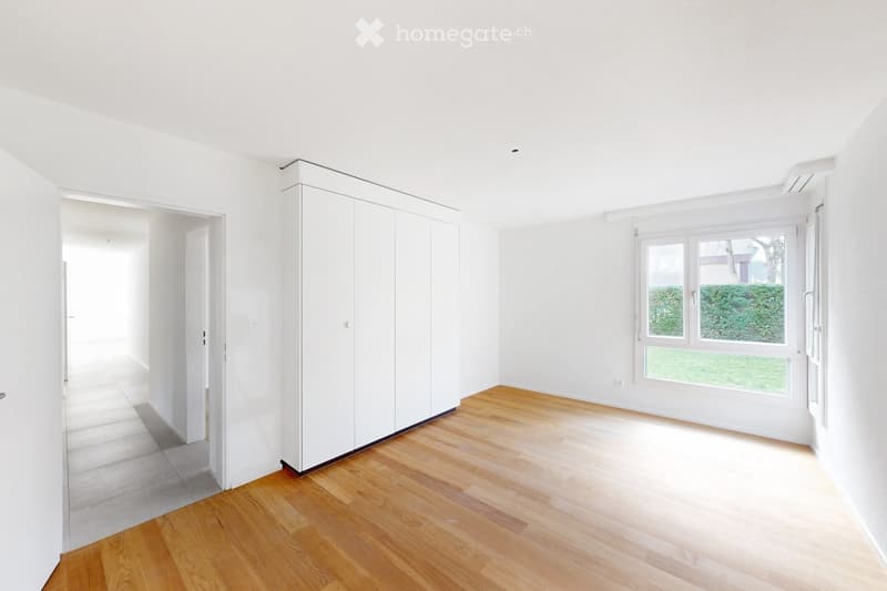 Empty room with white walls, wooden flooring, large window, and built-in closet. No furniture or equipment present.