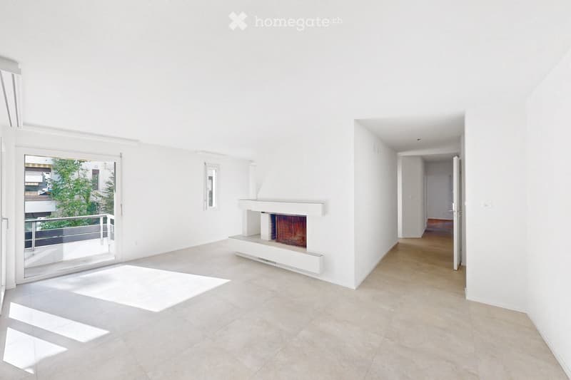 Bright, minimalist living room with white walls, tiled floor, fireplace, large sliding glass door leading to balcony, and hallway access.