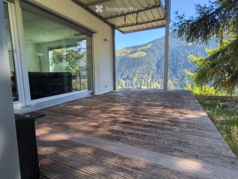 Wooden deck with large glass doors leading to a scenic mountain view.