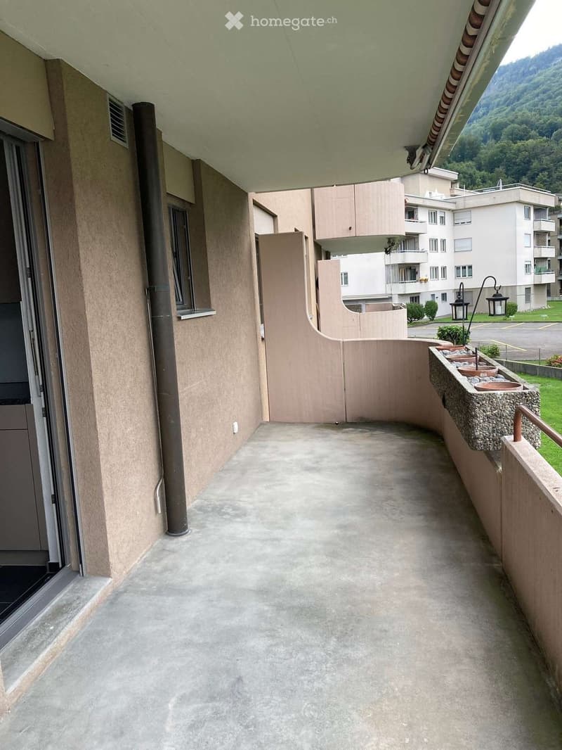 Balcony with concrete floor, wooden railing, and small stone planters on the right side.