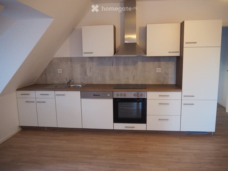 Modern kitchen with white cabinets, stainless steel appliances, and wooden flooring.