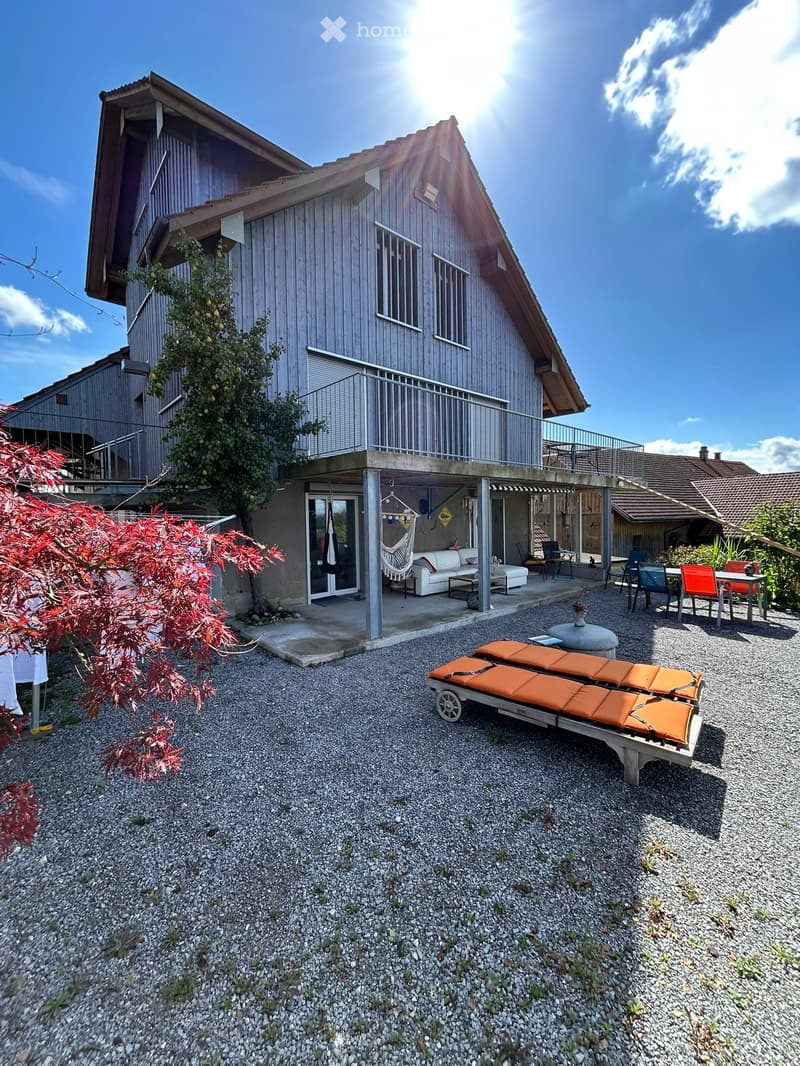Outdoor area with gravel ground, sunbeds, sofa, coffee table, chairs, and a balcony with a view.