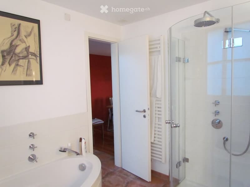 Bathroom with a bathtub, shower, towel rack, white tiles, and a wooden chair