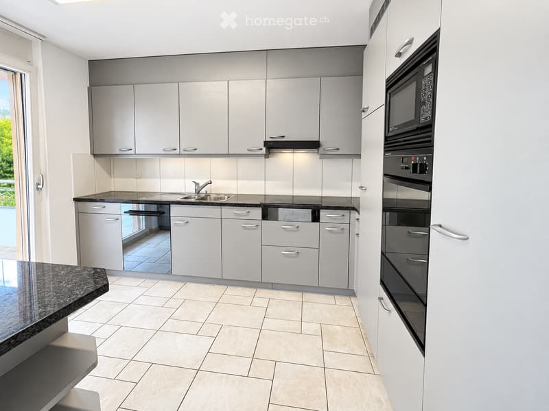 Modern kitchen with white cabinets, stainless steel appliances, granite countertop, and tiled flooring.