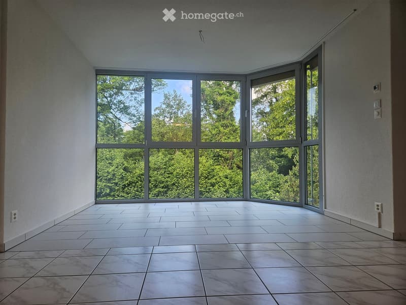 Empty room with large windows, tiled floor, and white walls.