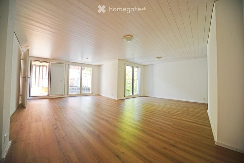 Empty room with wooden flooring, white walls, and large sliding glass doors leading to a balcony or outdoor area.
