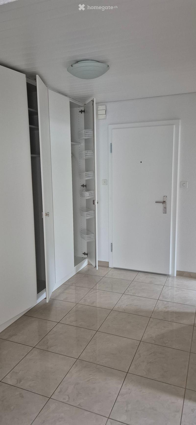 Empty room with tiled floor, white walls, and built-in storage cabinets with wire baskets inside.