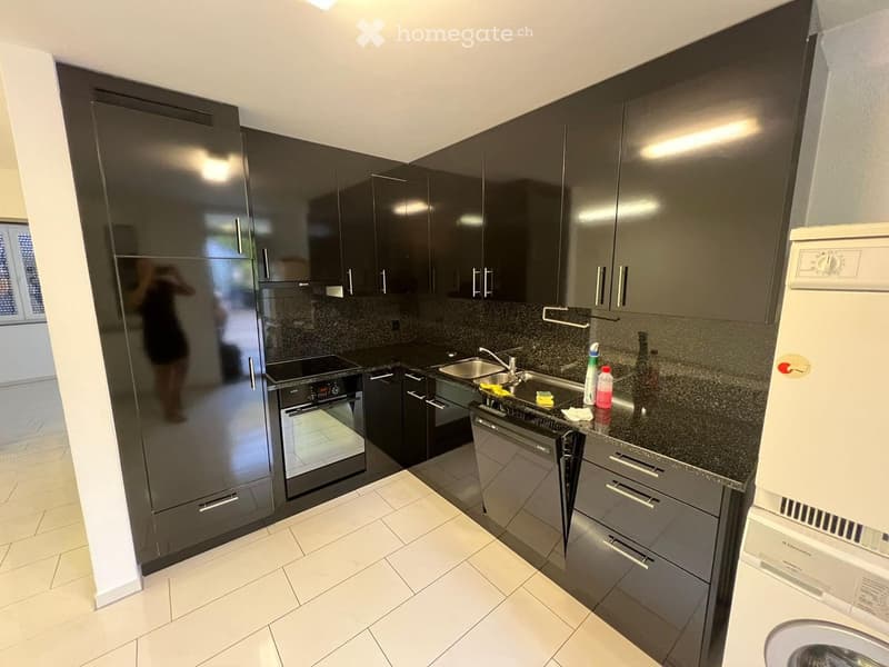 Modern kitchen with dark grey cabinets, stainless steel appliances, and a granite countertop.