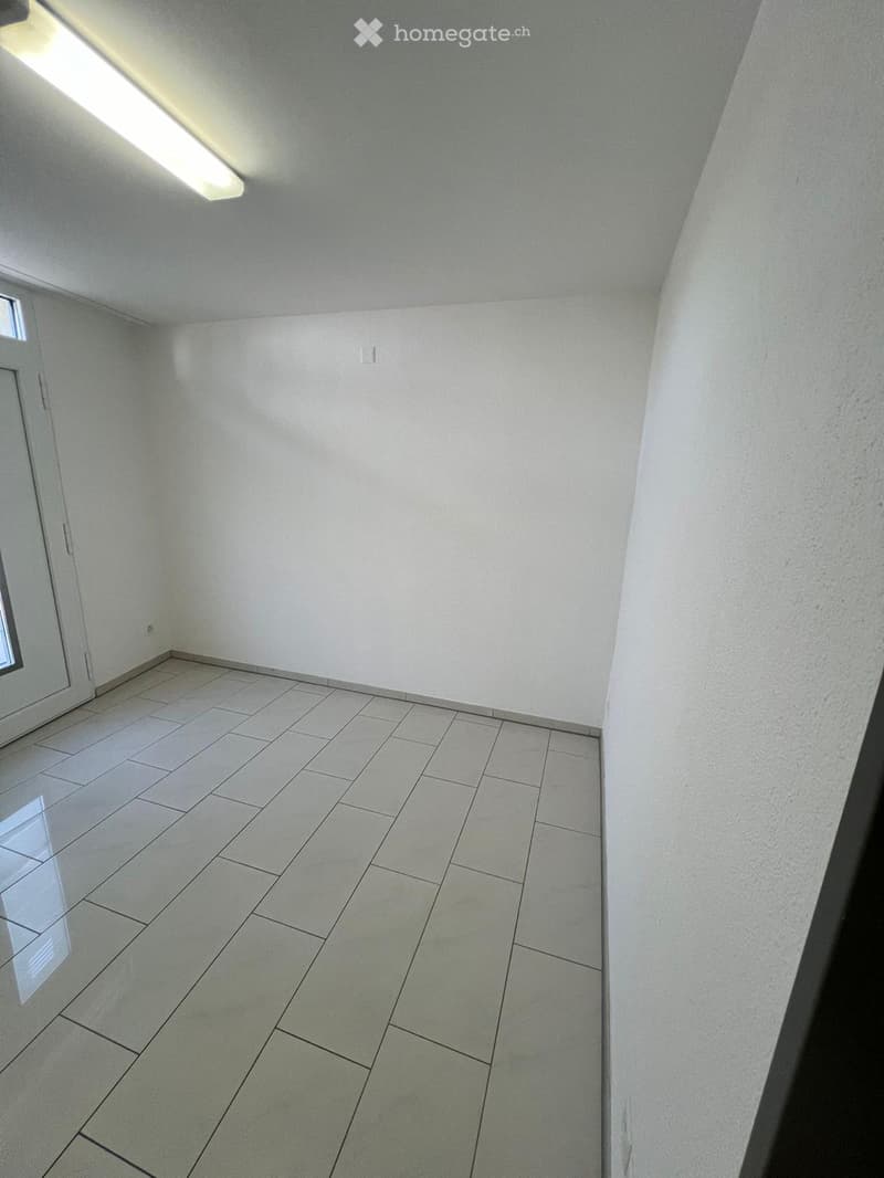 Empty room with white walls, tiled floor, and a small window on the left side.