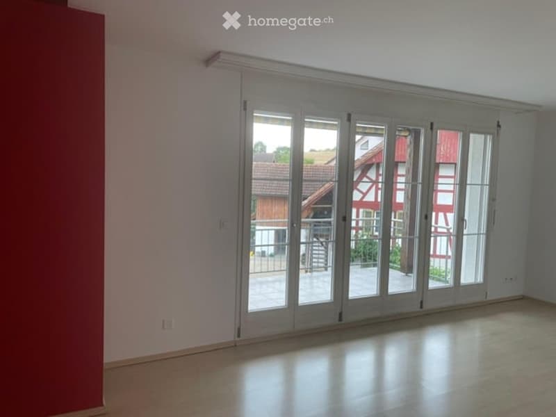 Empty room with large sliding glass doors leading to a patio, light-colored walls, and a polished floor.