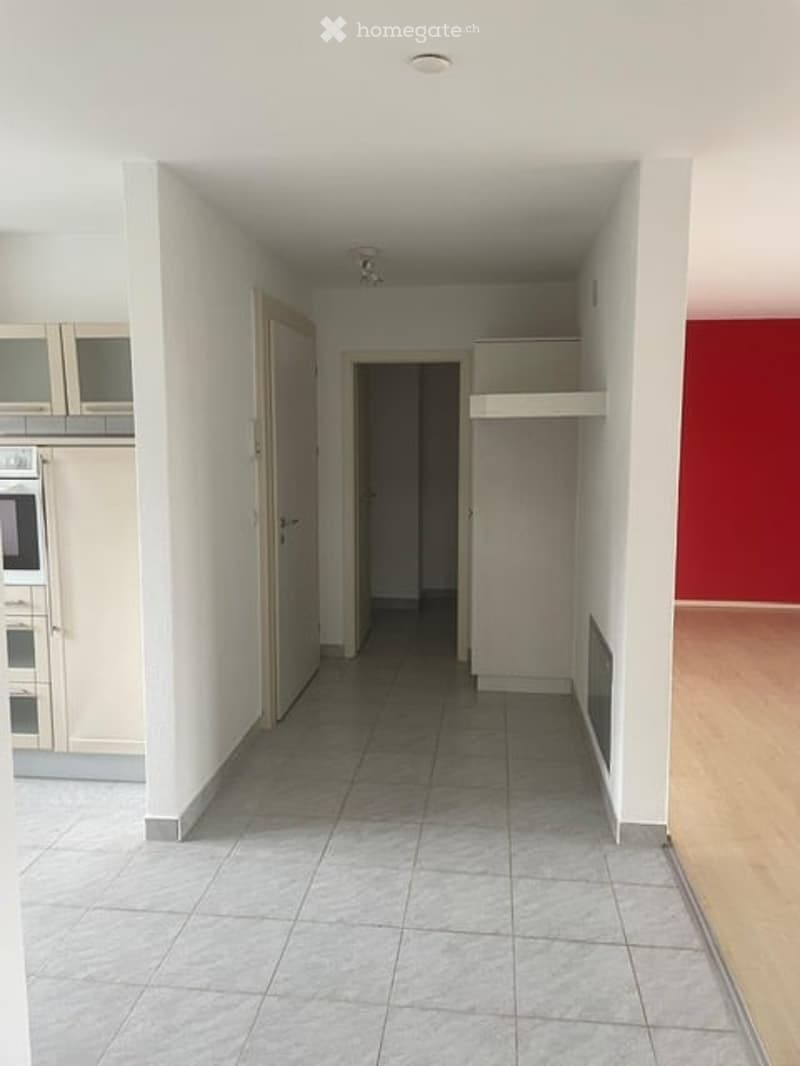 Empty hallway with tiled floor, white walls, and open doorways leading to other rooms. No furniture or equipment visible.