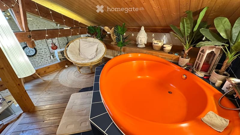 Cozy bathroom with an orange bathtub, a wicker hanging chair, a round rug, a clock, decorative items, and plants.
