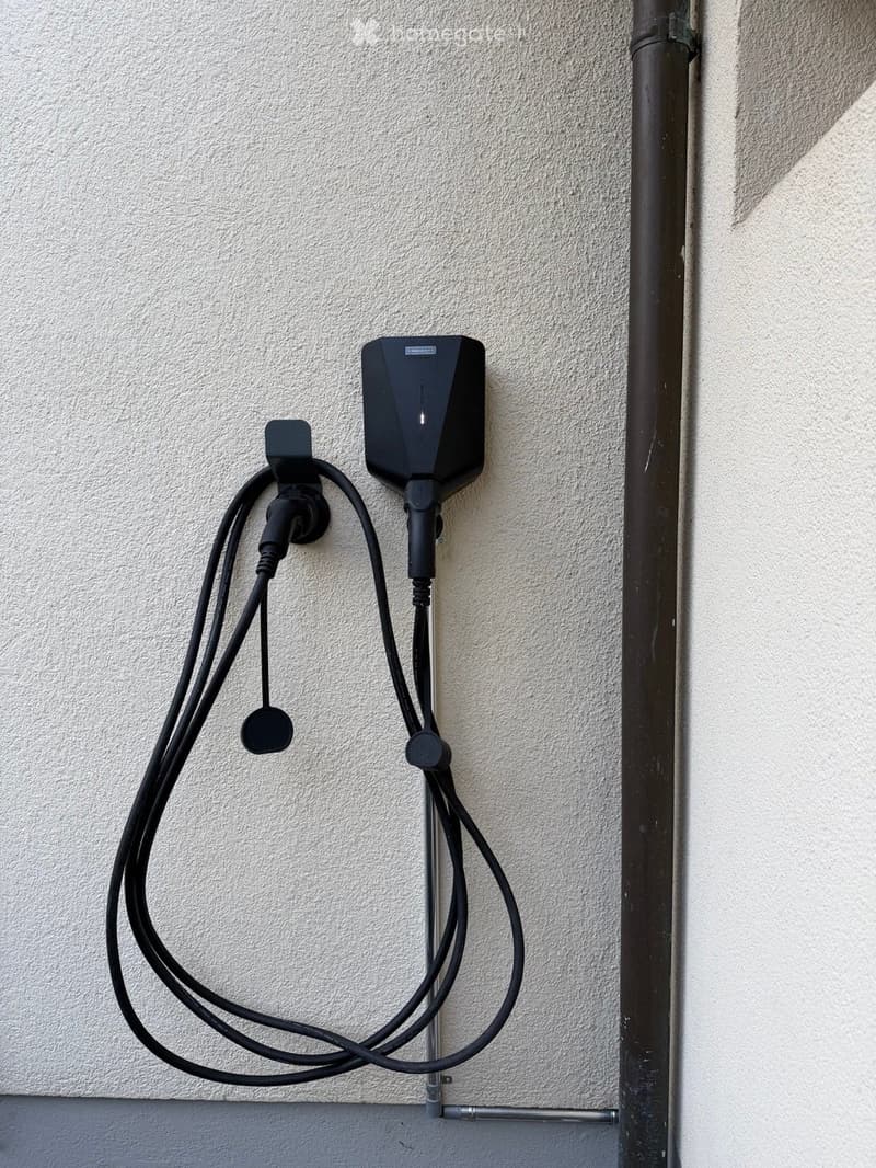 An electric vehicle charging station mounted on a wall with multiple cables connected.