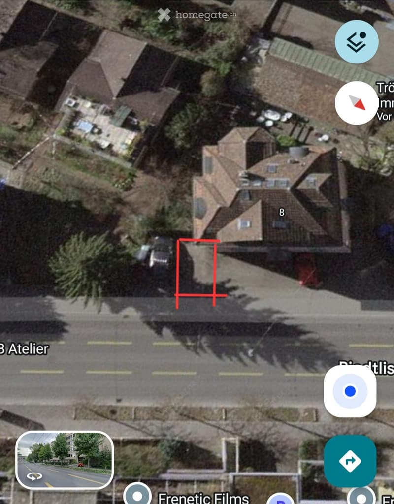 Aerial view of a residential area showing multiple houses with pitched roofs, surrounded by trees and a road.