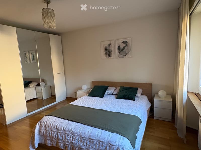 Modern bedroom with a large bed, nightstands, a wardrobe with a mirror, and decorative artwork on the wall.