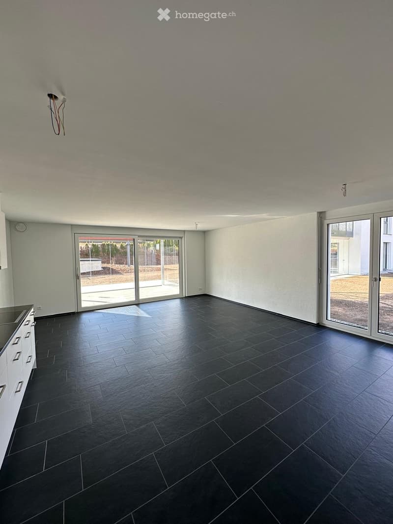 Empty room with dark tiled floor, white walls, and large sliding glass doors leading to an outdoor area.