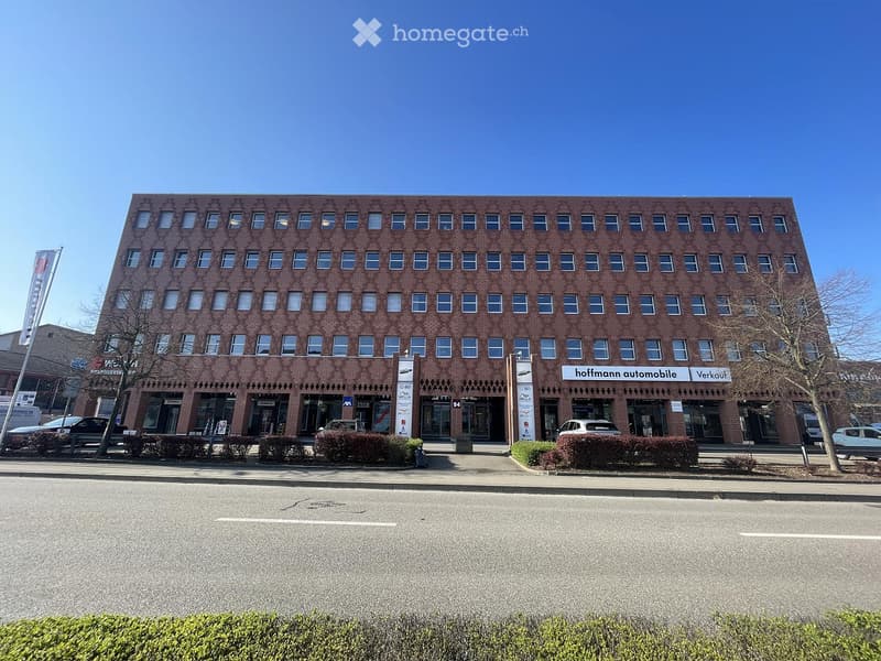 Multi-story brick building with numerous windows and commercial signage for "hoffmann automobile" visible on the ground floor.