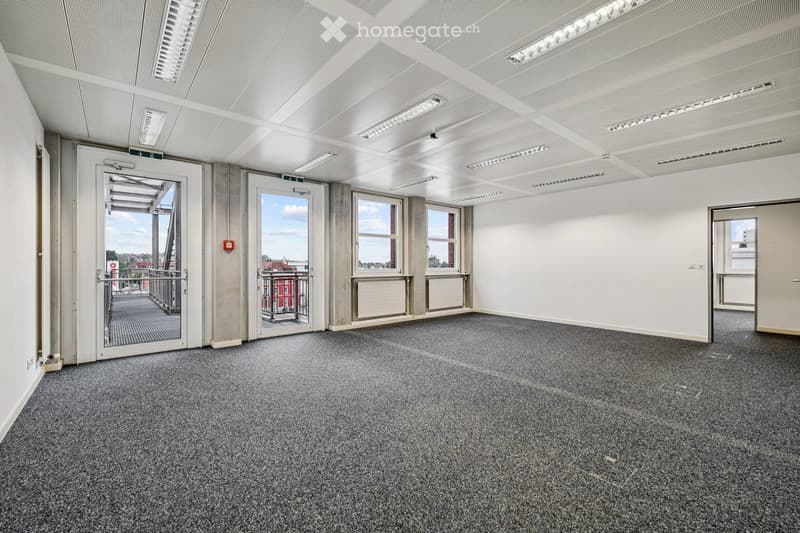 Empty room with grey carpet, white walls, large windows, and a door leading to a balcony.
