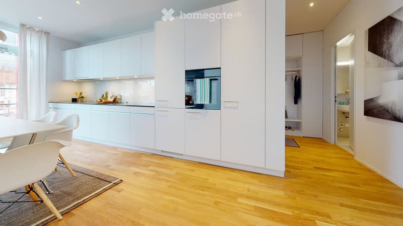 Modern kitchen and dining area with white cabinets, a round dining table with chairs, and a small plant on the counter.
