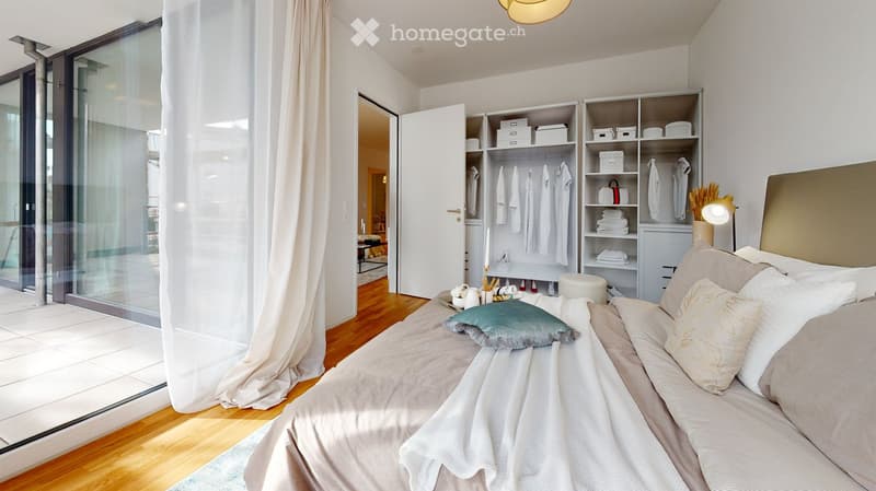 Modern bedroom with a large bed, pillows, a nightstand, a wardrobe with shelves, and a large window with a curtain.