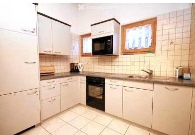 A modern kitchen with white cabinets, a microwave, an oven, a sink, and a coffee maker on the counter.