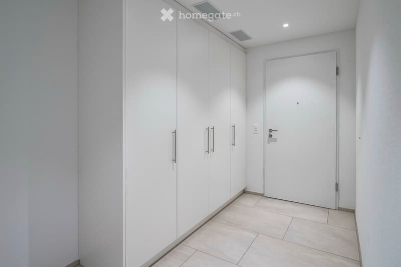 Closet with several compartments and a white door on a tiled floor