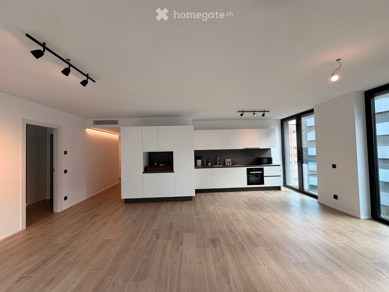Modern, minimalist kitchen with white cabinets, wooden flooring, and large windows. Features include an oven, microwave, and sink.