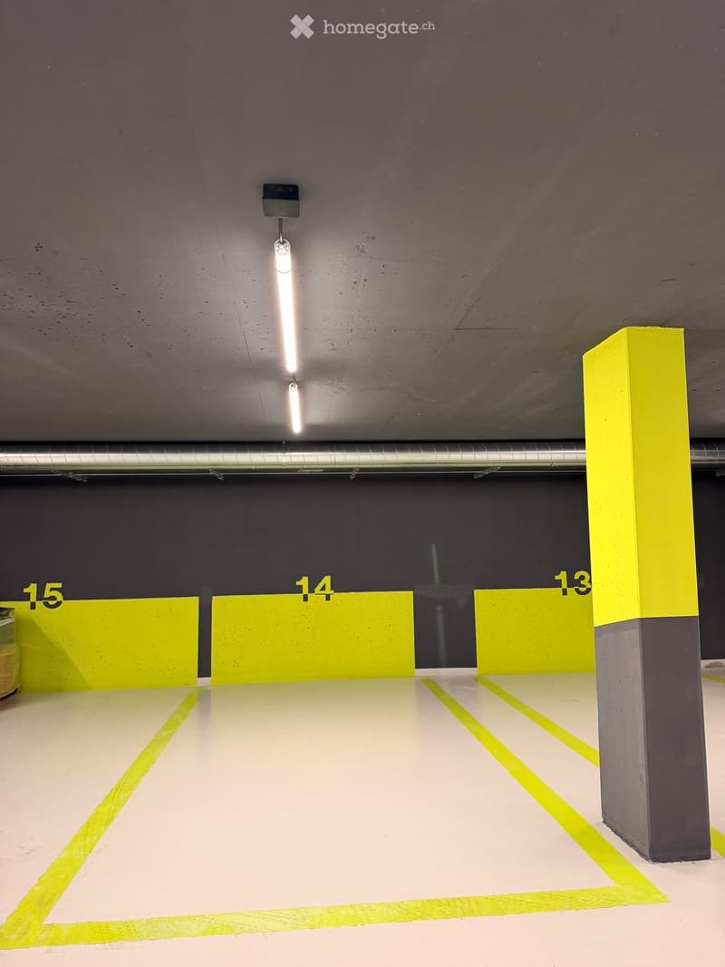 Underground parking area with numbered parking spots, yellow markings, and concrete pillars.
