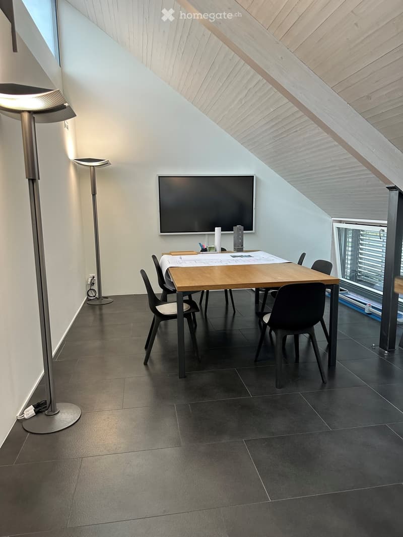 Modern room with dark tiled floor, wooden table, chairs, large screen, and floor lamp near the window.
