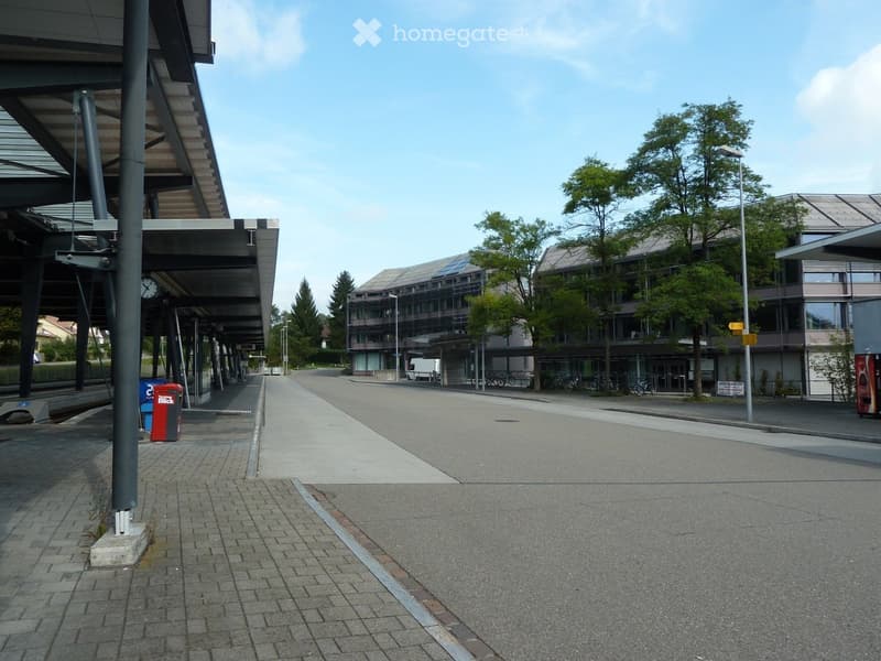 Modern building with a covered walkway, bicycles parked nearby, and a clear sky in the background.