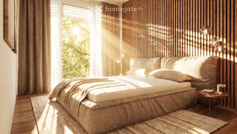 Modern bedroom with a large bed, nightstand, table lamp, and books. Natural light streams in through a window with sheer curtains, complemented by warm wooden paneling and a patterned rug.