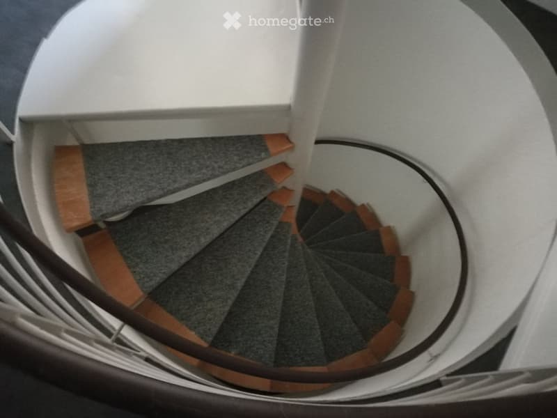 Spiral staircase with wooden steps and a modern, curved design, leading upwards.