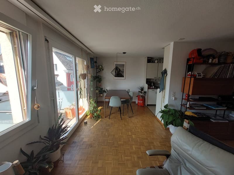 open living room with dining area, wooden floor, large windows, balcony, plants, table, chairs, couch