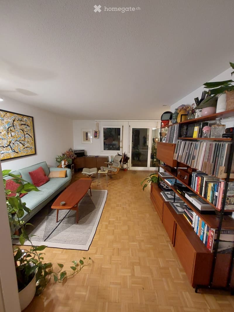 living room with wooden floor, couch, coffee table, rug, bookshelf, plants, picture frame, glass doors