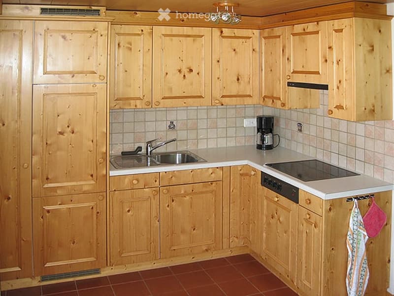 Wooden kitchen with light-colored cabinets, stainless steel sink, electric stove, and coffee maker on the counter.