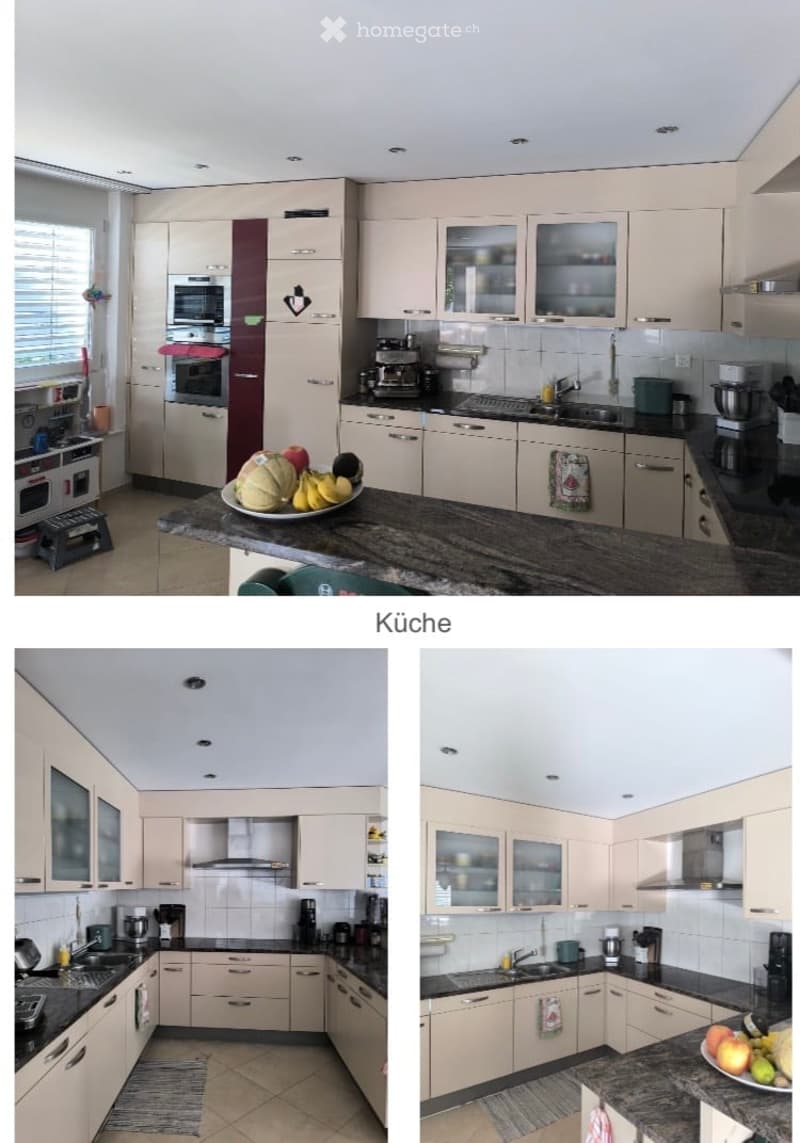 Modern kitchen with light-colored cabinets, granite countertop, stainless steel appliances, and various kitchen items including a plate of fruits on the counter.